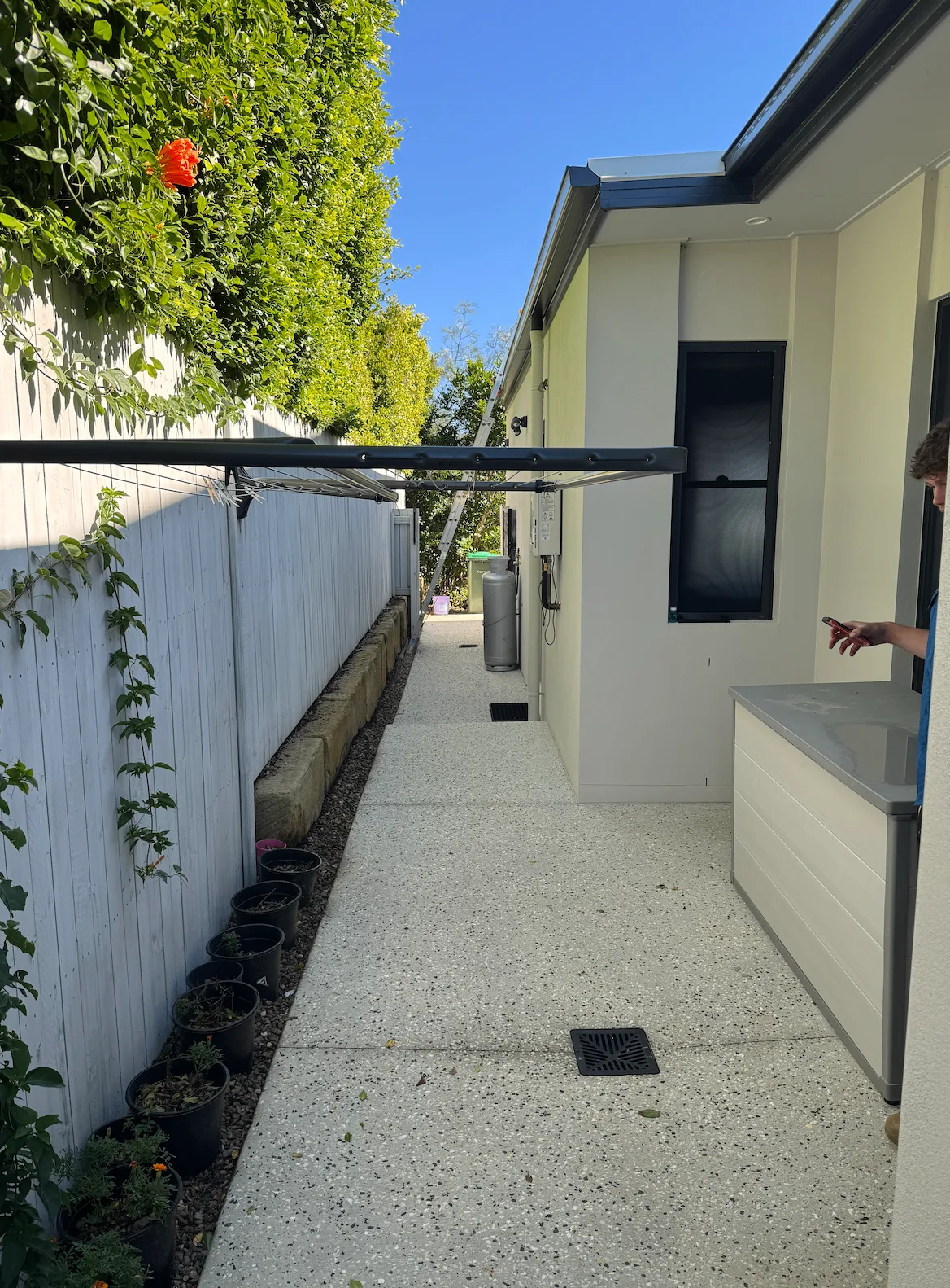 Clean exposed aggregate side path beside a white fence and clothesline