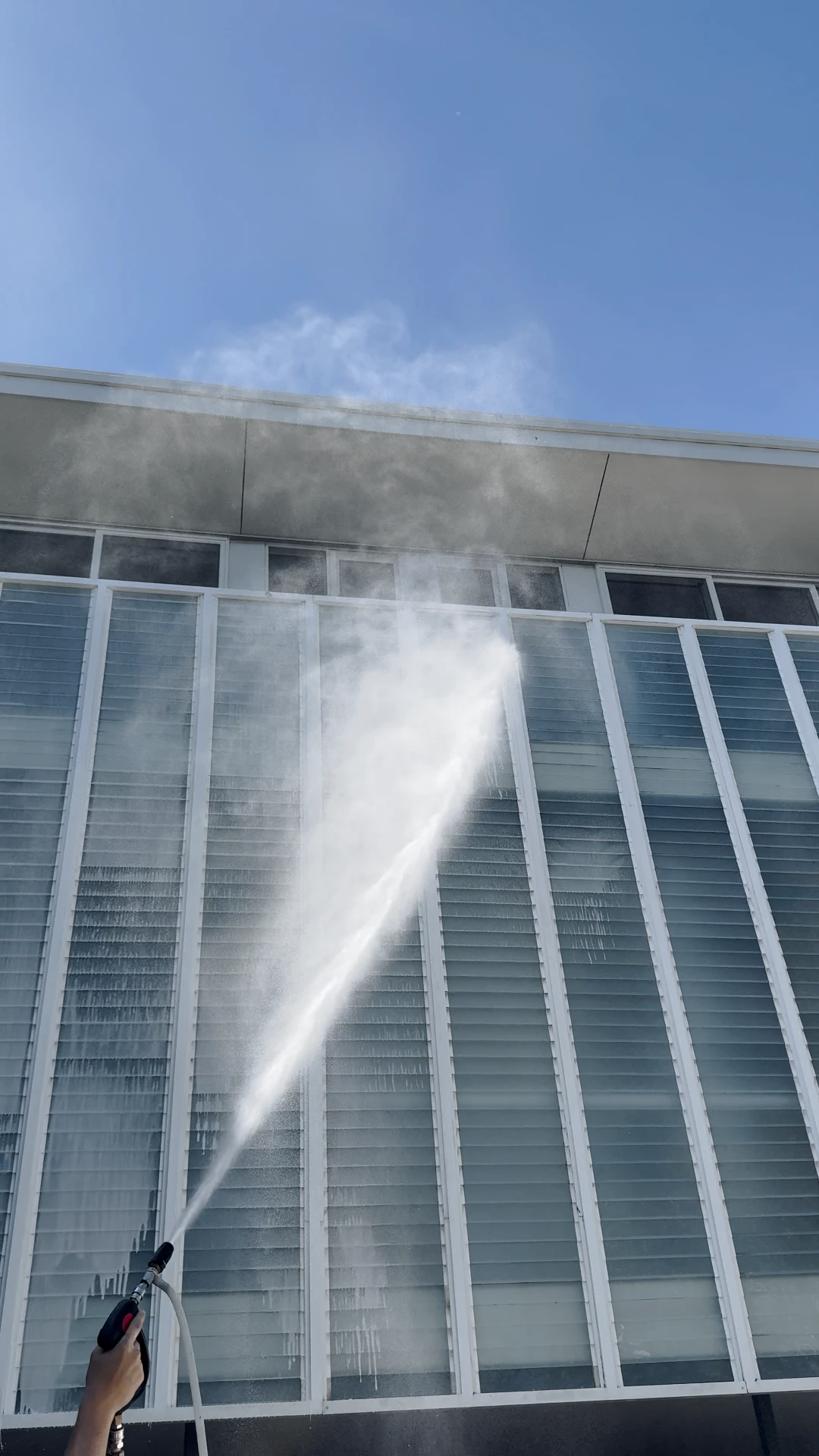 Washing the exterior of a modern home under a blue sky